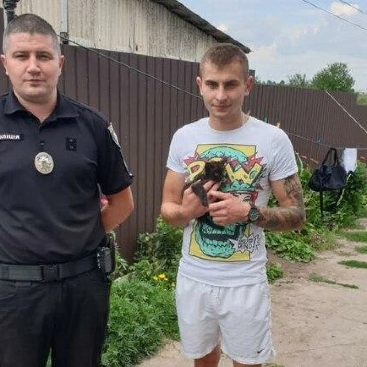 Чоловік, який викрав кошеня Магнолія, тримає тварину поряд з поліцейським після затримання