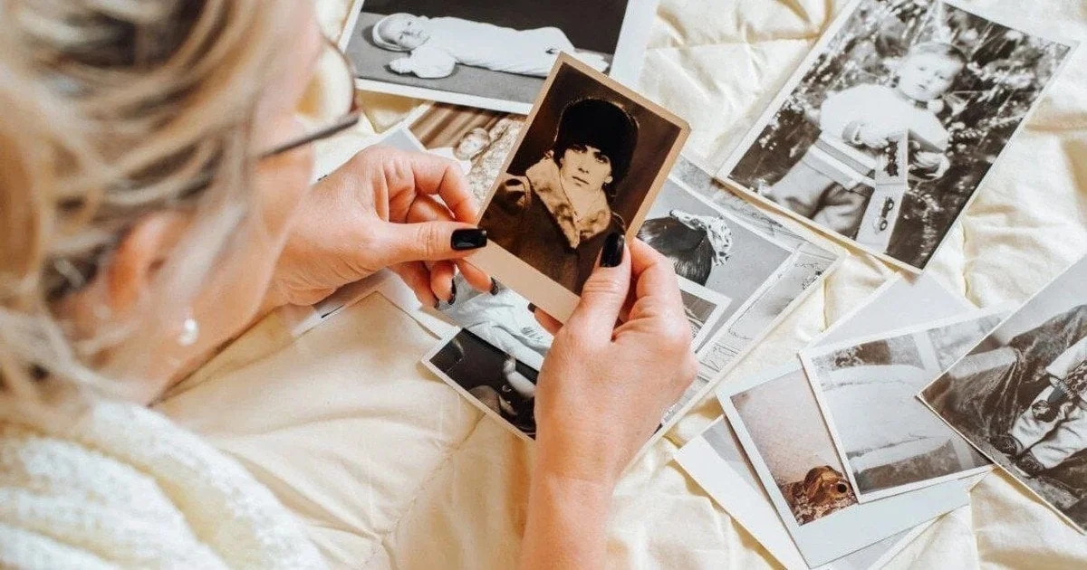 Жінка переглядає старі фотографії дитини, відчуваючи ностальгію за минулим