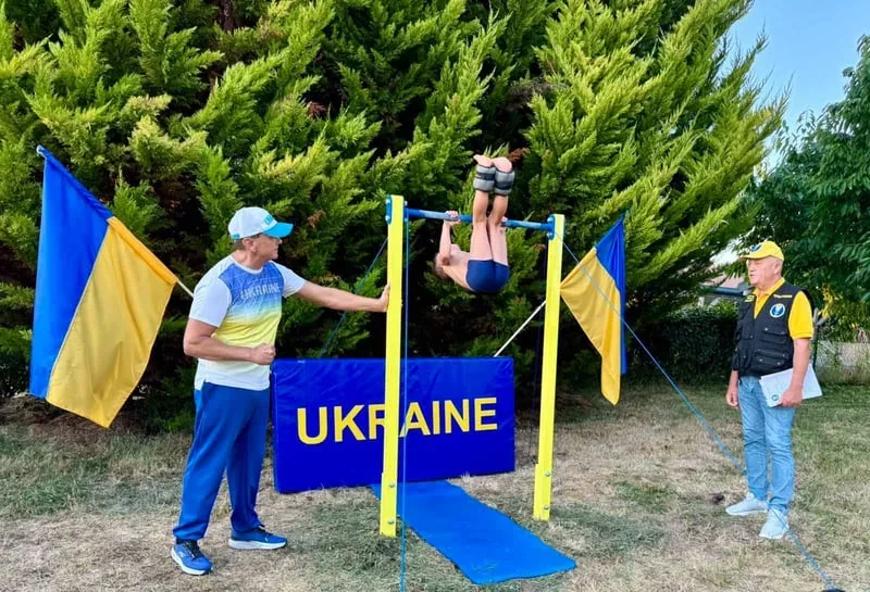 Філіп Нагорний виконує підйом з переворотом на перекладині з прапорами України