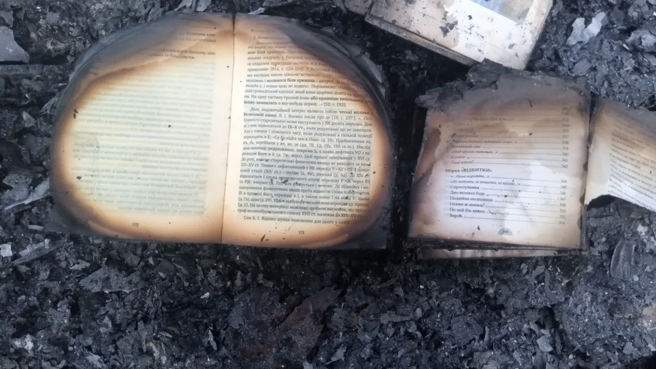Згорілі відкриті українські книжки лежать на чорному попелі